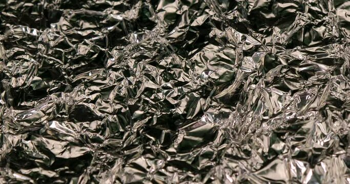 Background with silver wrinkled aluminium foil in rotating motion