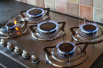 Blue gas flames burning on a gas hob burner, kitchen gas cooker