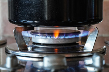 Blue gas flames burning on a gas hob burner, kitchen gas cooker with pot