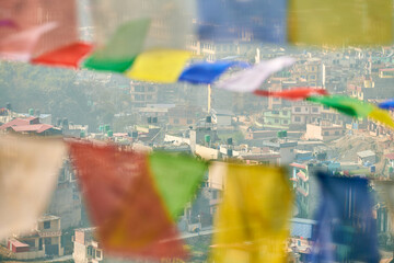View of Kathmandu with lot of low rise buildings through colorful prayer flags, hilltop view of...