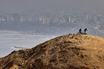 Downhill bike riders descending the lines of Morro Solar at Chorrillos With Lima city on the background
