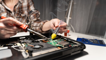 The master solders the microcircuit with a soldering iron