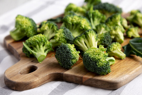 Organic Raw Broccoli Florets on a Wooden Board, side view.