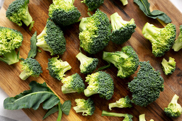 Organic Raw Broccoli Florets on a Wooden Board, top view.
