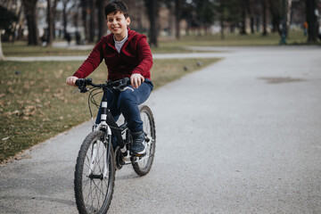 A young boy is seen having fun riding his bicycle in an urban park, conveying a sense of freedom and joy.