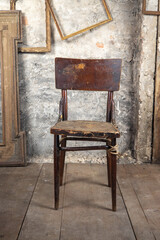 Defective old broken chair in an old dirty room with other vintage things