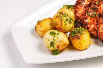 A plate of food with a large grilled octopus on it and a side of potatoes