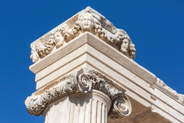 Detail of an ancient Corinthian capital with acanthus leaves and four Medusa heads against a clear blue sky. Aphrodisias, Geyre, Aydin, Turkey (Turkiye)