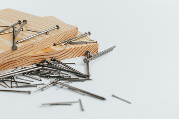 Two boards lie on a white background and nails are scattered nearby. space for text
