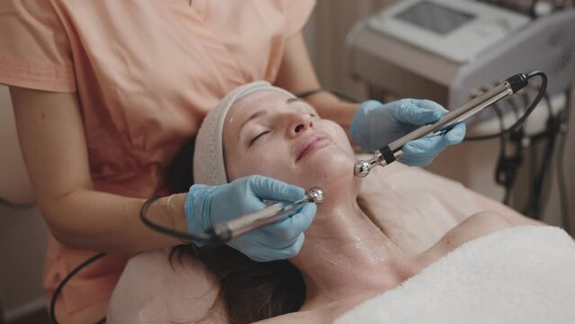 Aesthetician performs a microcurrent facial treatment on a relaxed female client in a professional spa setting, enhancing skin rejuvenation.