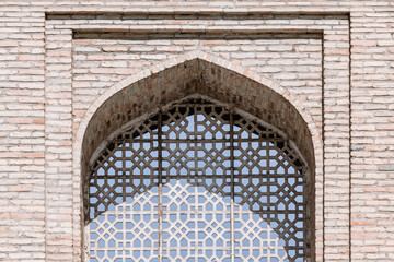 Tashkent Hazrati Imam mosque, window traditional outer decoration. Time-worn brick arch frames a delicate blue and white lattice window. Tashkent, Uzbekistan
