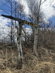 Beach Trail Sign with a sky background in the trees