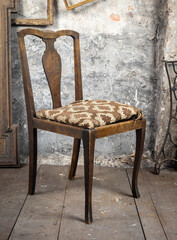 Defective old broken chair in an old dirty room with other vintage things