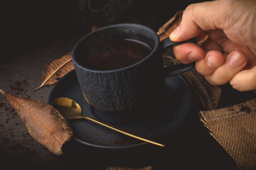 Cup of Coffee with autumn leaves on a black background, vintage tone