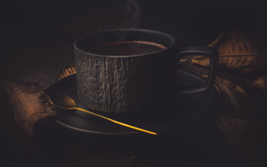 Coffee cup and autumn leaves on a dark background, vintage tone