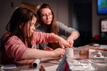 A girl and a woman are absorbed in creating a craft with clay, a dynamic scene of family...
