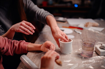Fototapeta na wymiar Close-up of hands carefully molding clay, capturing the essence of tactile learning and artistic expression during a family crafting session