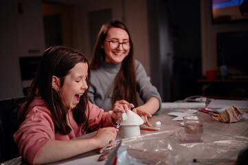 The sheer delight of a girl sculpting with clay is shared with her mother, capturing the essence of...
