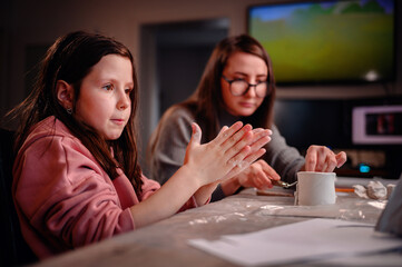 The sheer delight of a girl sculpting with clay is shared with her mother, capturing the essence of...