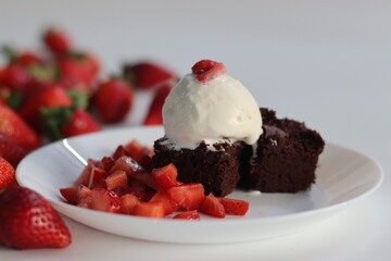 Chocolate brownie with fresh strawberries and a scoop of creamy vanilla ice cream