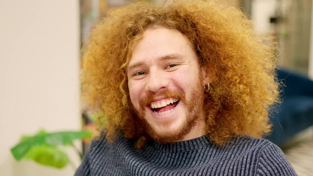 Man with curly hair smiling at camera in a coworking