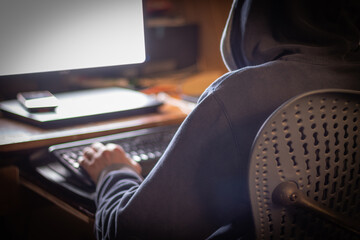 Anonymous man in sweatshirt works on computer