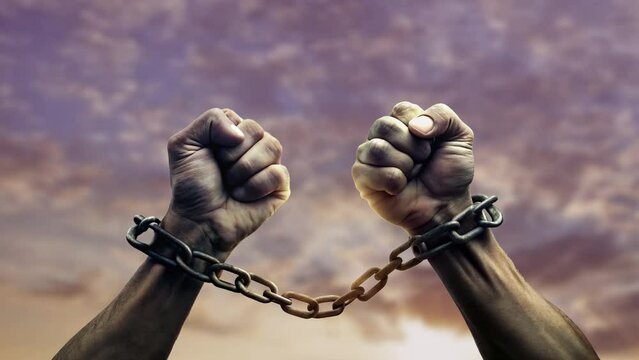 2 hands shackled in chains to commemorate Emancipation Day with a blurry sky background