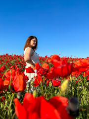 Cute woman in white dress in poppy field