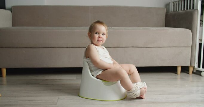 Side view of adorable smiling girls sitting on chamber pot,potty training hygiene. child learning sit on toilet wc seat at home. Kid about two years old. High quality 4k footage