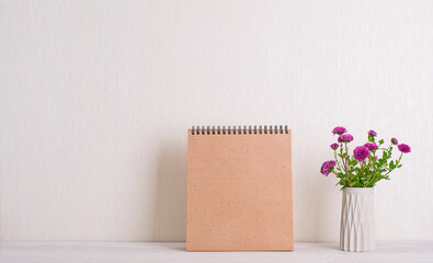 Chrysanthemum flowers and notebook mockup over white wall.