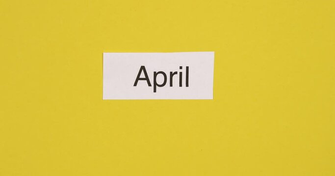 Month names changing on colorful paper background. Time passing, annual calendar, seasons concept. Top view, 4K stop motion animation.