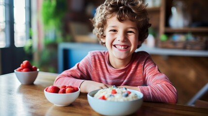 Happy boy sitting at a table with a plate of fruit having a meal at home. Young boy in casual clothes preparing to eat fruit while smiling and looking at the camera. Cheerful boy getting ready to eat. - 760796600