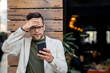Business man looking shocked at mobile phone possible bad news, gossip, scam or financial online...
