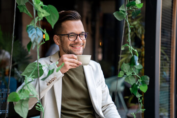 Happy smiling relaxed man, young professional businessman entrepreneur sitting in modern outdoor...