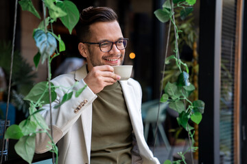 Happy smiling male business person enjoying his morning coffee in the city Cafe.