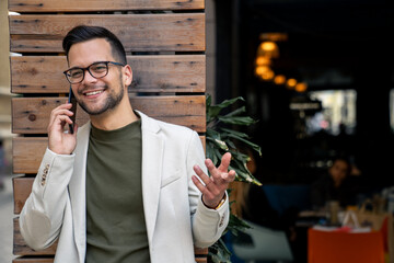 Smiling young entrepreneur making plans with his business associates while talking on the phone.