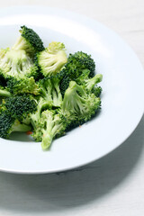 Raw broccoli on white insulated plate