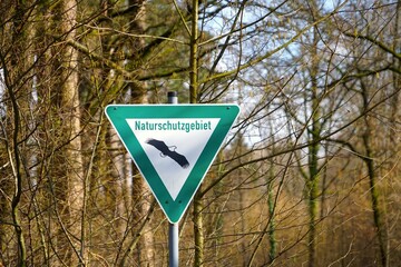 Naturschutzgebiet, Schild im Hintergrund ein Wald mit Kiefern und Laubbäumen im Frühjahr, Natur,...