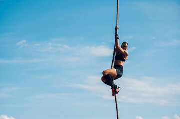 Fit female partake in an obstacle course race during which climbing a rope