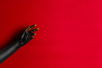 Black and gold colors painted woman's hands on her skin with red background. High Fashion art concept