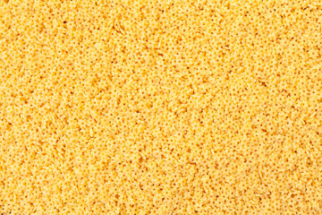 Uncooked yellow small stars shaped pasta background. Top view