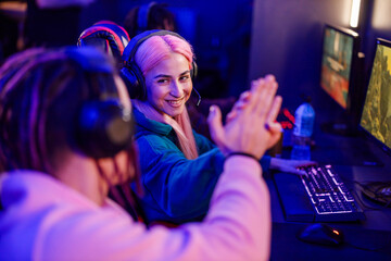 Woman gamer giving high five to a friend and celebrating victory on a tournament