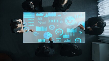 Top down aerial of collaborate professional diverse business people discuss marketing strategy with hologram of marketing data analysis graph, diagram or financial profit investment plan. Directorate.