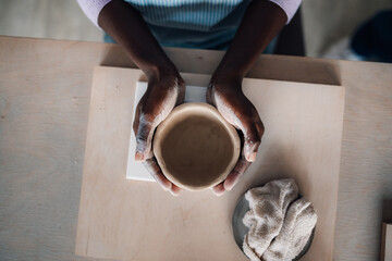 Top view of interracial woman's hand holding a clay pot on pottery class