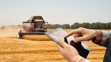 Farmer with digital tablet on a background of harvester. Smart farming concept