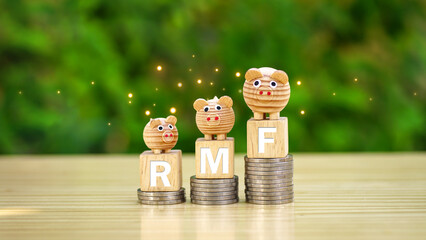 Rows of money coins stacks with RMF word and piggy bank on wooden cube on nature garden background...
