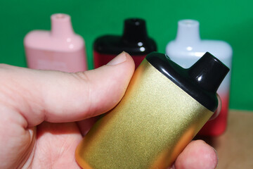 Electronic cigarette in hand close-up on a green background. Vaping devices in the best quality.