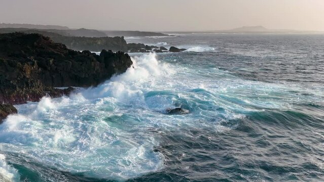 4K aerial slow motion view of ocean and giant waves crashing at rocky cliff with splashing and white foam. Lanzarote. Canary islands, Spain