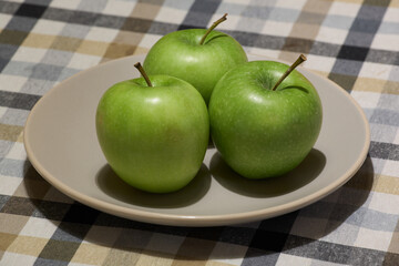 Green apples on a ceramic plate