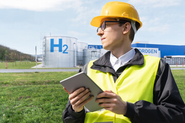 Engineer with tablet computer on a background of Hydrogen factory.